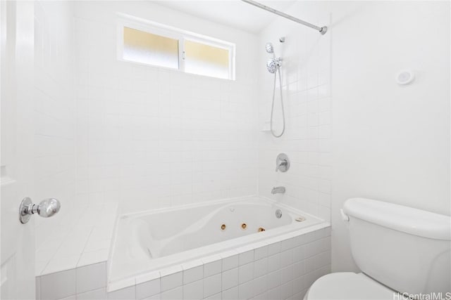 bathroom with toilet and tiled shower / bath