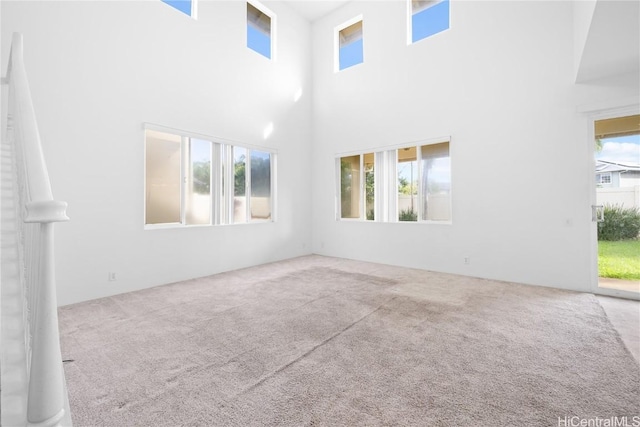 unfurnished living room with carpet flooring, a high ceiling, and a wealth of natural light