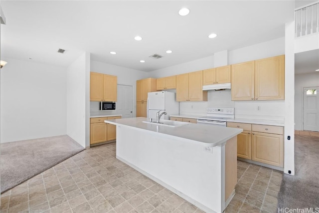 kitchen featuring light brown cabinets, white appliances, light carpet, and a kitchen island with sink