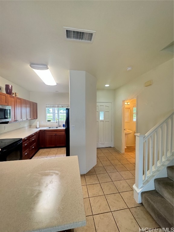 kitchen with sink, light tile patterned floors, and black appliances