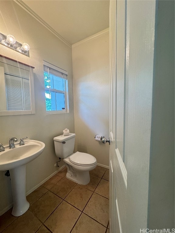 bathroom with tile patterned floors, crown molding, sink, and toilet