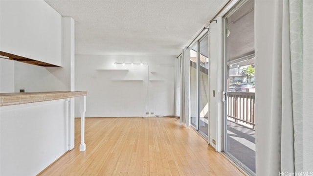 hallway with a textured ceiling and light wood-type flooring