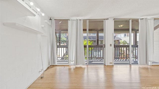 spare room with expansive windows, light wood-type flooring, and a textured ceiling