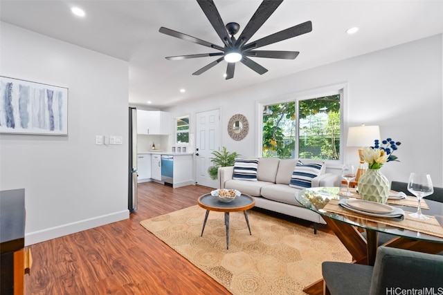 living room featuring light hardwood / wood-style floors, ceiling fan, and a healthy amount of sunlight