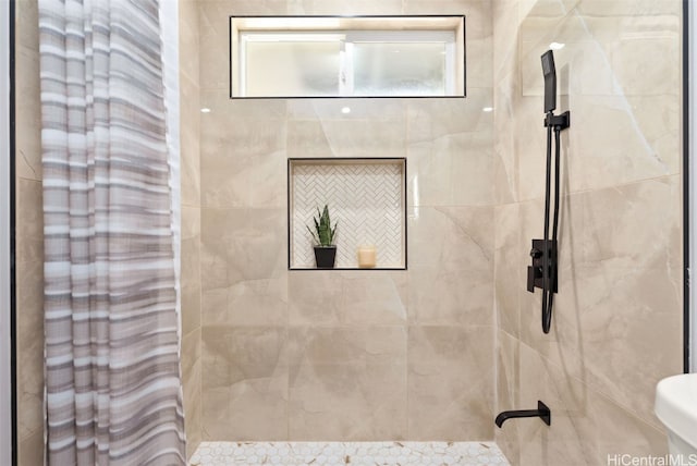 bathroom featuring a tile shower and toilet