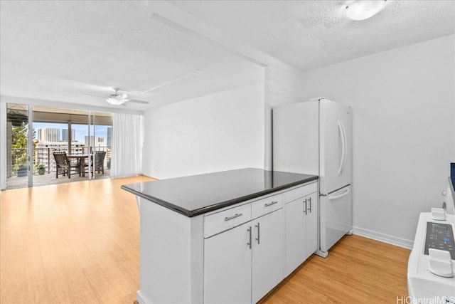 kitchen featuring ceiling fan, white fridge, a textured ceiling, white cabinets, and light wood-type flooring