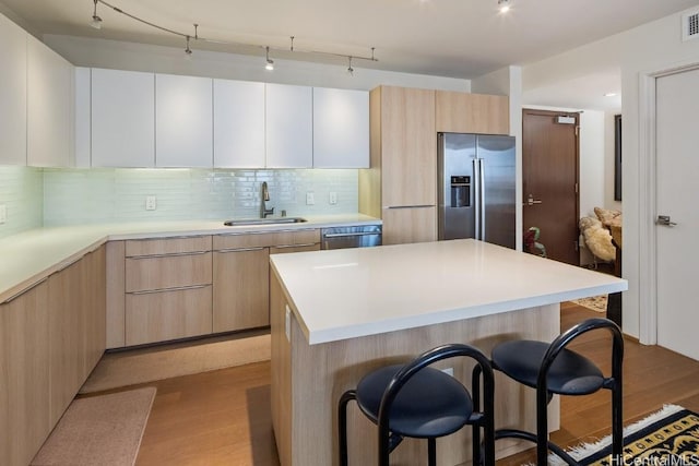 kitchen featuring appliances with stainless steel finishes, light wood-type flooring, white cabinetry, and sink