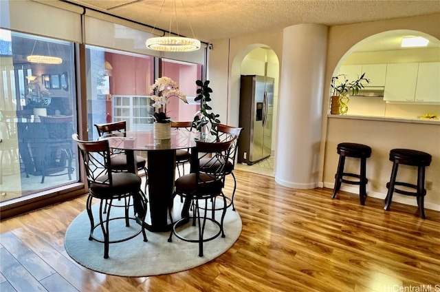 dining area featuring an inviting chandelier, a textured ceiling, and light wood-type flooring