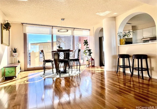 dining space featuring wood-type flooring and a textured ceiling