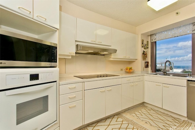 kitchen with a textured ceiling, stainless steel appliances, white cabinetry, and sink