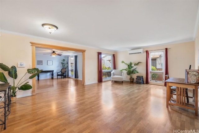 living room with a wall mounted air conditioner, light hardwood / wood-style flooring, ceiling fan, and ornamental molding