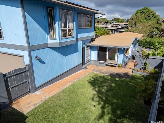 back of property featuring a lawn and fence