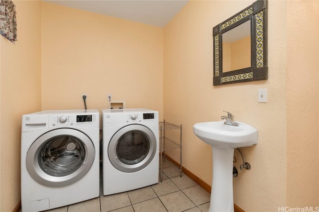 laundry room featuring light tile patterned floors, washer and clothes dryer, and sink