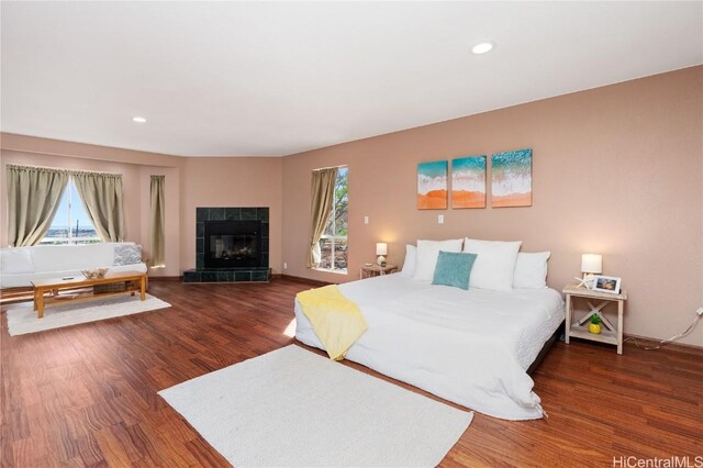 bedroom featuring dark wood-type flooring and a tile fireplace