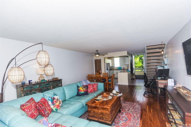 living room with a textured ceiling, ceiling fan, and dark wood-type flooring