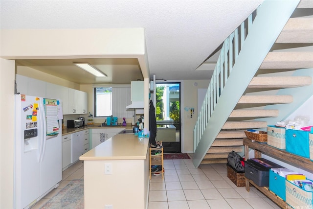 6770 Hawaii Kai Dr Unit 24, Honolulu, HI 96825 - kitchen with white refrigerator with ice dispenser, light tile patterned floors, light countertops, white cabinetry, and a peninsula