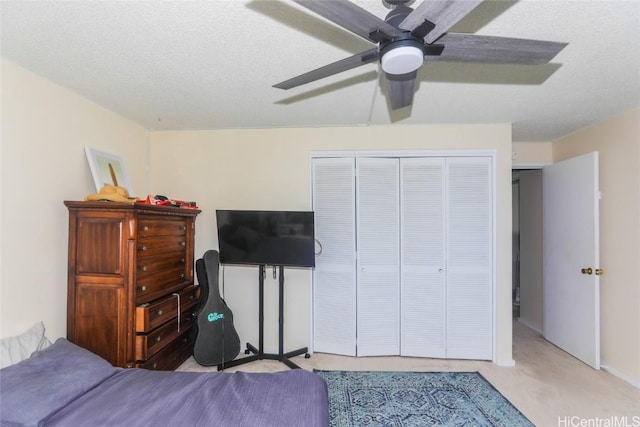 bedroom with ceiling fan, a closet, light colored carpet, and a textured ceiling