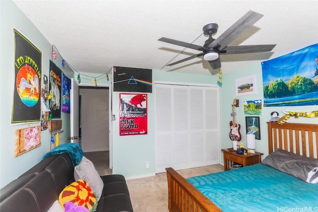 bedroom with ceiling fan, a closet, light colored carpet, and a textured ceiling