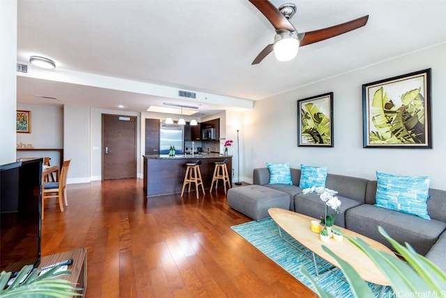 living room featuring ceiling fan and dark hardwood / wood-style flooring