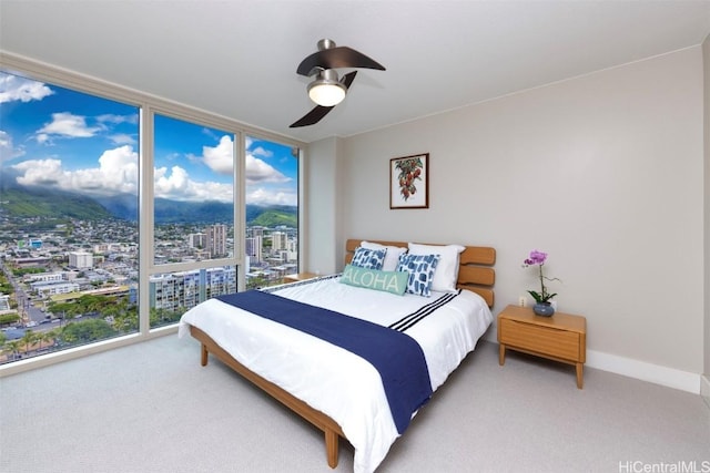 bedroom with carpet floors, a wall of windows, and ceiling fan