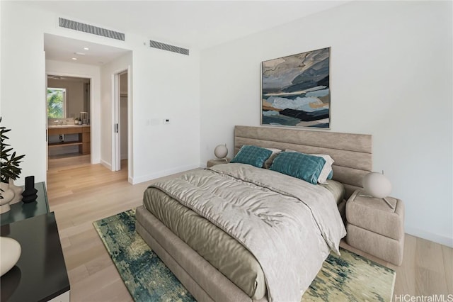 bedroom with hardwood / wood-style floors and ensuite bath