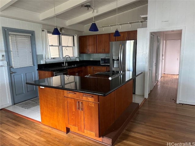 kitchen with appliances with stainless steel finishes, pendant lighting, lofted ceiling with beams, light hardwood / wood-style flooring, and a center island