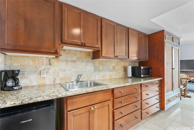 kitchen featuring sink, light stone countertops, a textured ceiling, appliances with stainless steel finishes, and light tile patterned flooring