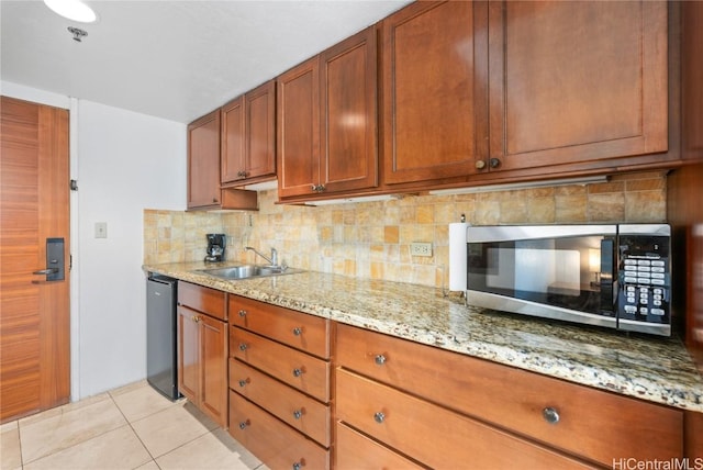 kitchen featuring dishwasher, backsplash, sink, light tile patterned floors, and light stone counters