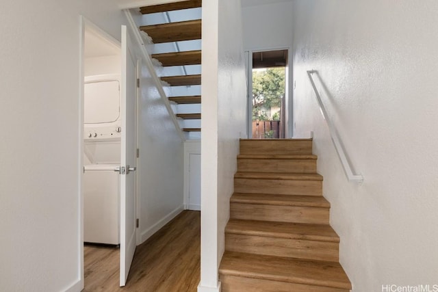 stairs with hardwood / wood-style floors, beam ceiling, and stacked washing maching and dryer