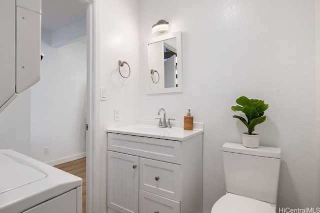 bathroom featuring washer / dryer, vanity, toilet, and hardwood / wood-style floors