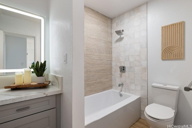 full bathroom featuring vanity, tiled shower / bath combo, and toilet