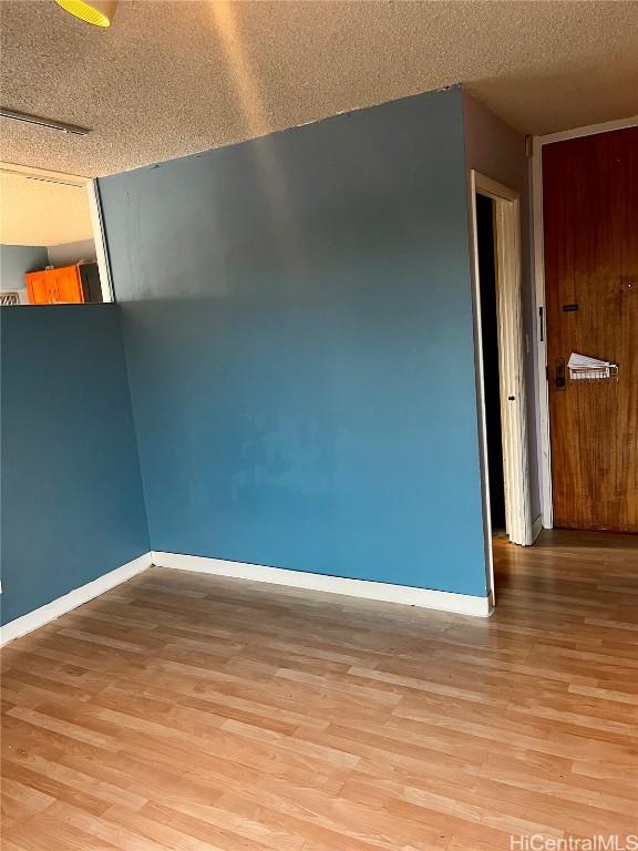 unfurnished room featuring a textured ceiling and light wood-type flooring