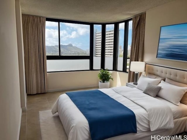 bedroom featuring a mountain view, a textured ceiling, and light tile patterned flooring