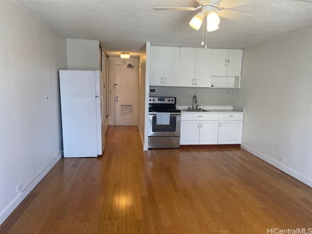 kitchen featuring hardwood / wood-style floors, stainless steel electric range, white refrigerator, and a textured ceiling