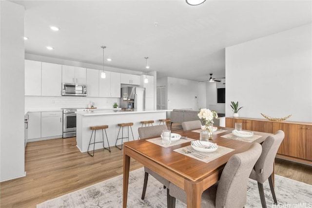 dining space with light hardwood / wood-style floors and ceiling fan