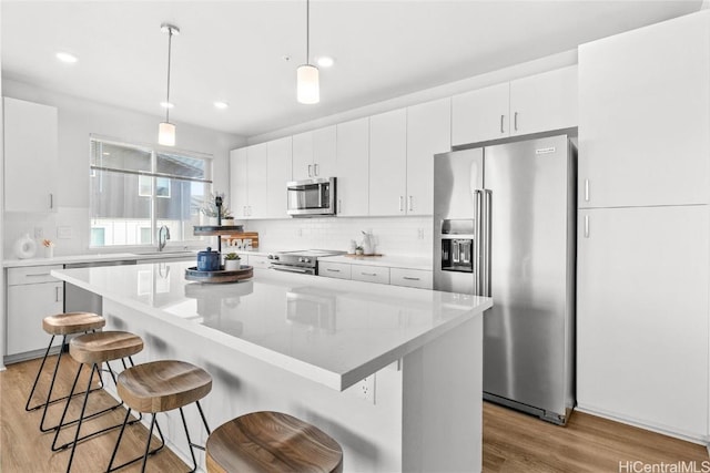 kitchen with pendant lighting, stainless steel appliances, a center island, and white cabinets