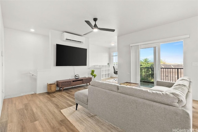 living room with ceiling fan, light hardwood / wood-style flooring, and a wall mounted AC