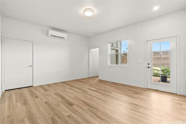 spare room featuring light hardwood / wood-style flooring and an AC wall unit