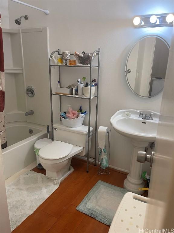 bathroom with hardwood / wood-style flooring, toilet, and shower / bathtub combination with curtain