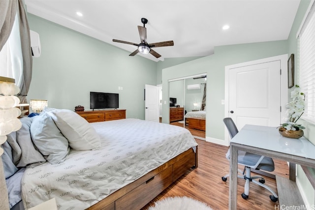 bedroom featuring ceiling fan, a wall unit AC, vaulted ceiling, a closet, and light wood-type flooring