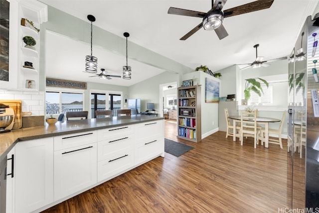 kitchen featuring white cabinetry, dark wood-type flooring, tasteful backsplash, lofted ceiling, and decorative light fixtures