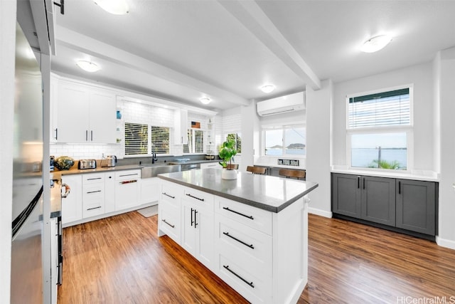 kitchen featuring white cabinets, dark hardwood / wood-style floors, a center island, and a wall mounted air conditioner