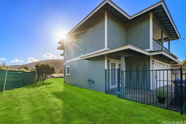 back of property featuring a lawn, a mountain view, and a garage