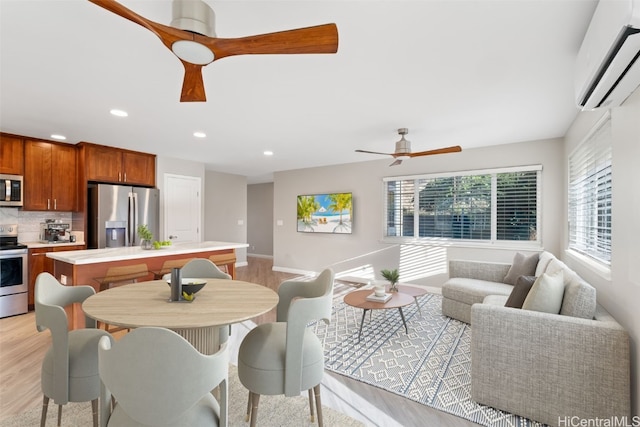 dining room with a wall mounted air conditioner, ceiling fan, and light hardwood / wood-style floors