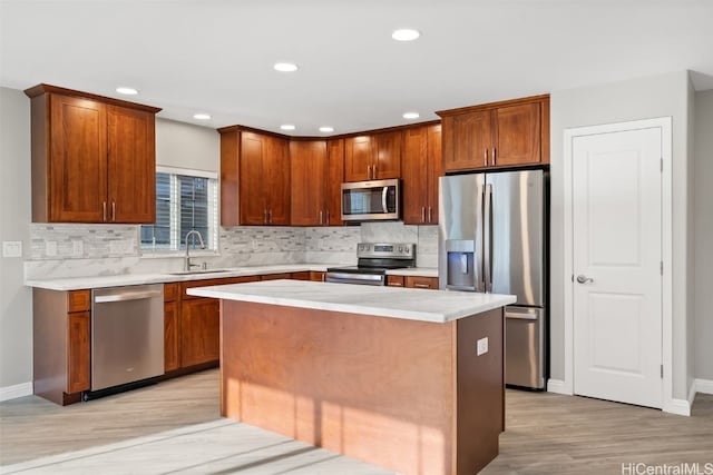 kitchen featuring appliances with stainless steel finishes, tasteful backsplash, sink, light hardwood / wood-style floors, and a kitchen island