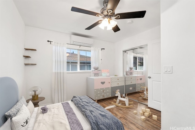 bedroom featuring an AC wall unit, ceiling fan, a closet, and wood-type flooring