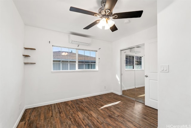 empty room with a wall mounted AC, ceiling fan, and dark wood-type flooring