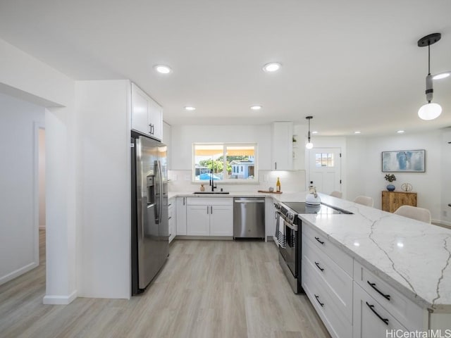 kitchen featuring stainless steel appliances, white cabinetry, hanging light fixtures, and sink