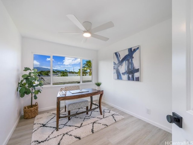 home office with light hardwood / wood-style floors and ceiling fan