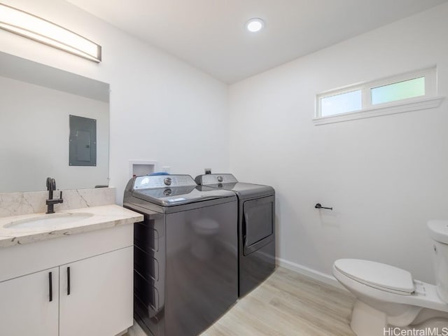 bathroom with electric panel, toilet, washer and clothes dryer, vanity, and hardwood / wood-style flooring